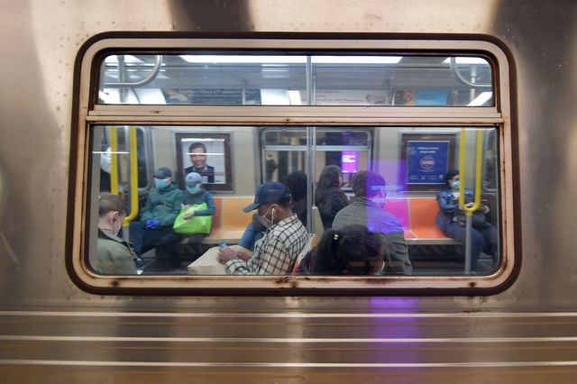 Subway riders seen through a subway train car window from the platform